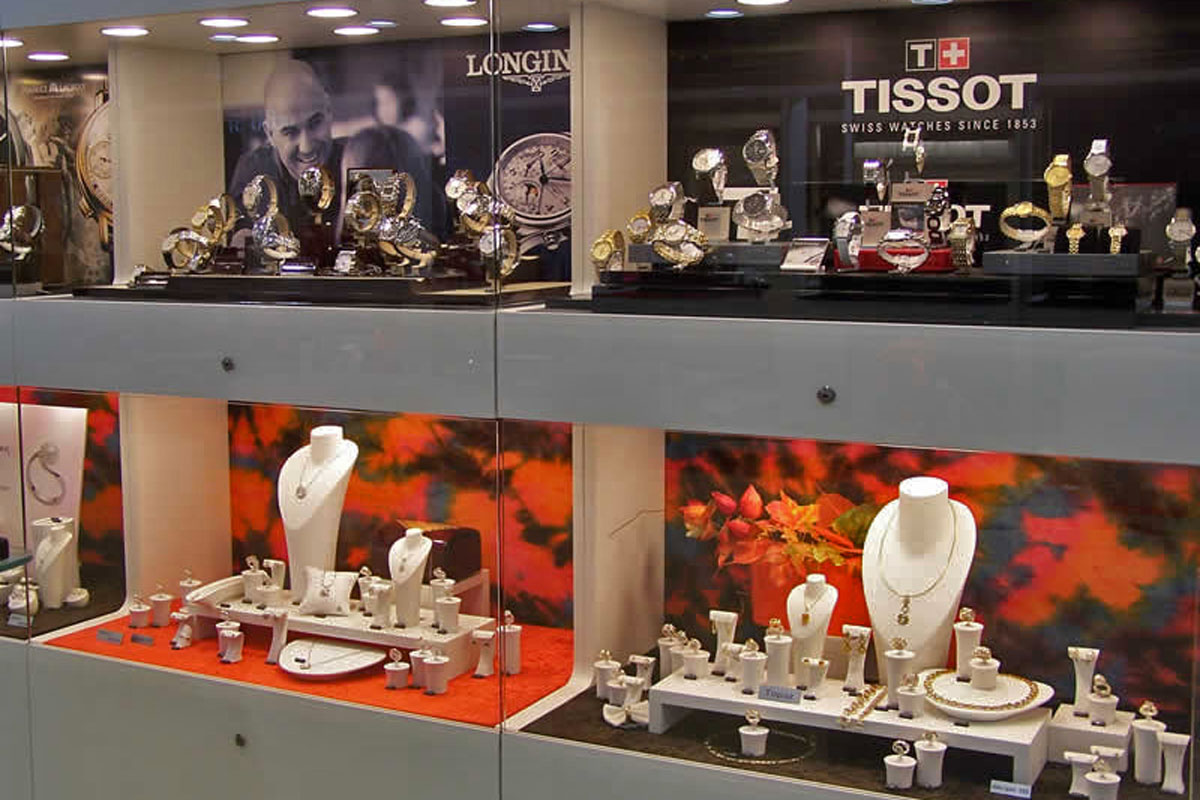 Aranžmá hodinek Tissot, Longin a šperků ve vitrínách Zhotovené dekorace ve vitrínách s naaranžovanými hodinkami Longin, Tissot a šperky