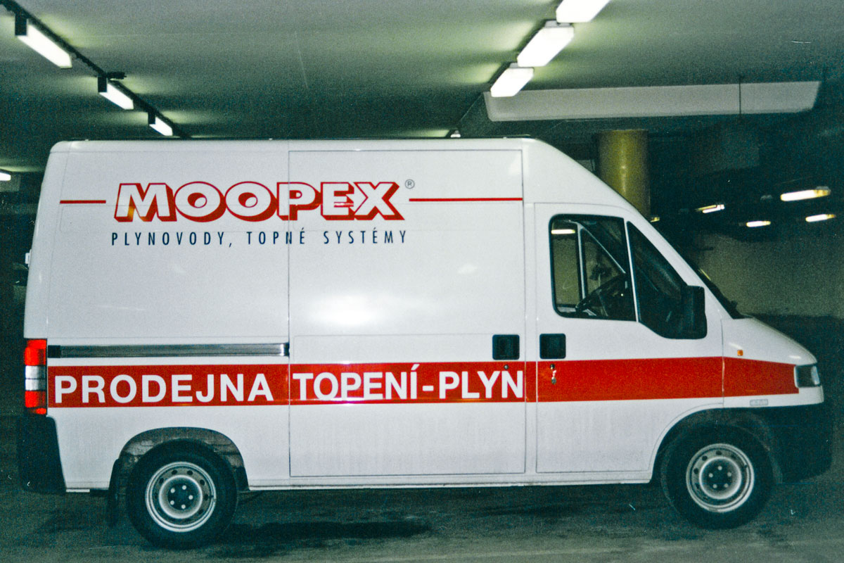 Auto firmy Moopex, Peugeot Boxer polepený červeným logem a pruhy. Moopex Peugeot Boxer v bílé barvě, nalepené logo a pruhy v červené, text černý