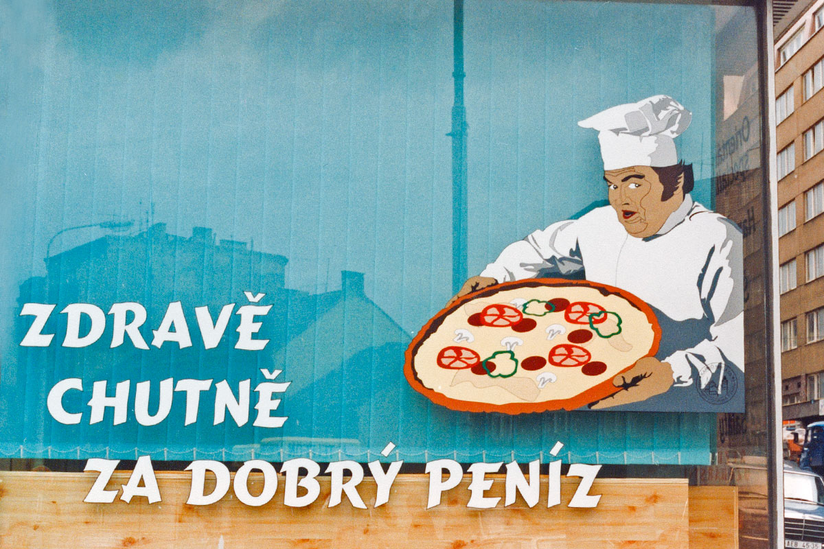 Detail kuchaře s pizzou na výloze, řezaná reklama rok 1993 Grafika kuchaře s pizzou zhotovena se samolepících folií s pomocí řezacího plotru